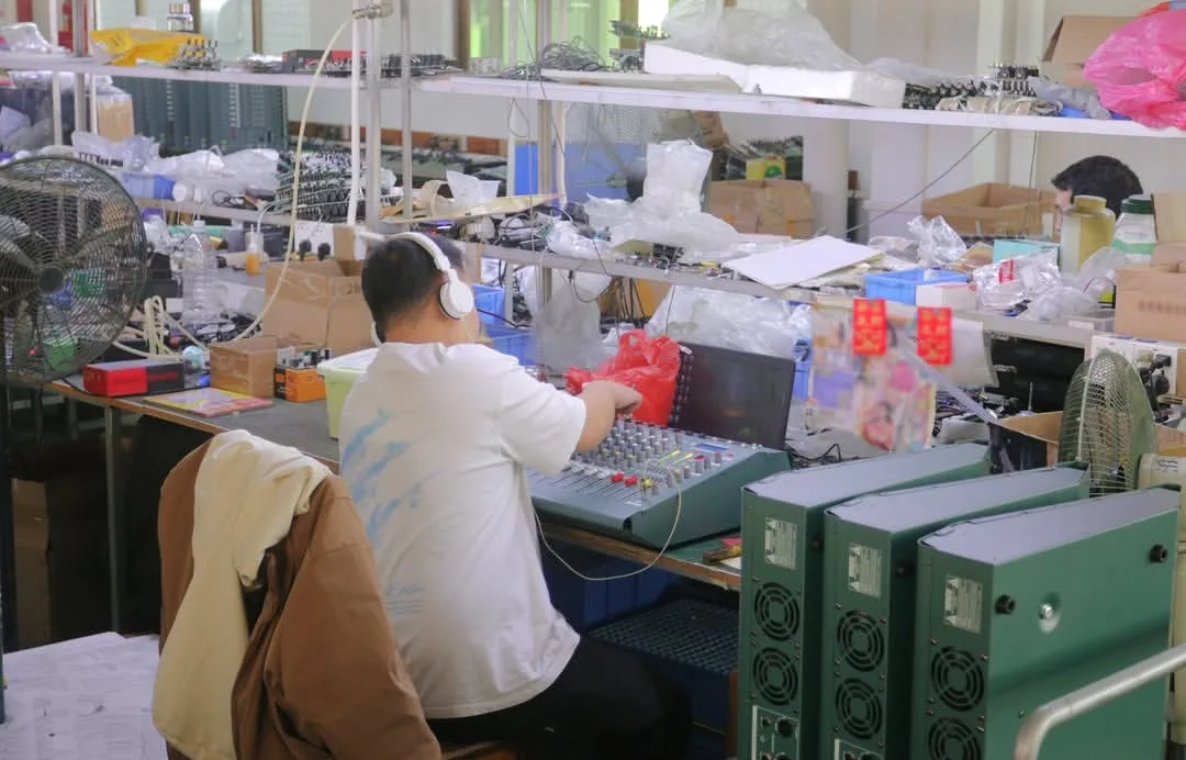 Live Console Acoustic QC & Listening Evaluation Station Audio QC engineer wearing reference monitor headphones testing multi-channel mixing consoles and finished green-cased audio equipment