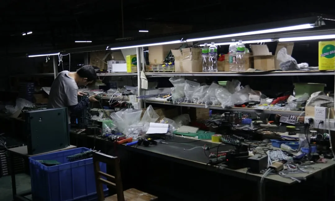 Dedicated Electronics Fabrication & Sub-Assembly Station ELM Audio production floor showing multi-tiered parts racks, illuminated workstation benches, and amplifier chassis sub-assembly
